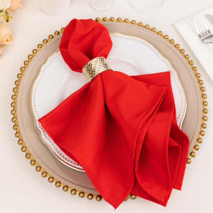 Red napkin with a gold ring on a decorative plate.