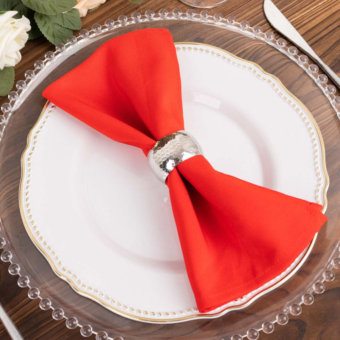 Red napkin with silver ring on a decorative plate.