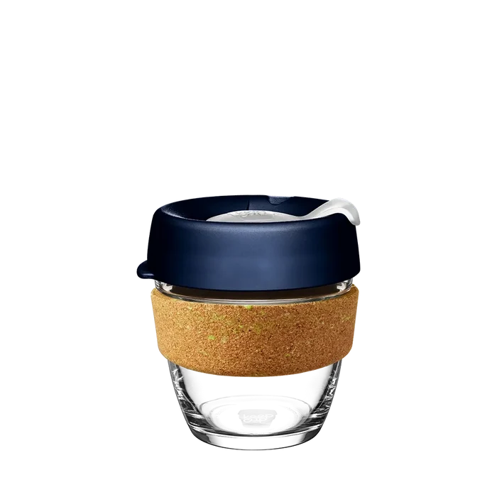 KeepCup Brew Cork in Spruce, small 8oz size, shown against a white background. The reusable cup features a clear glass body, natural cork band, and deep navy blue lid with a plastic sipper plug.