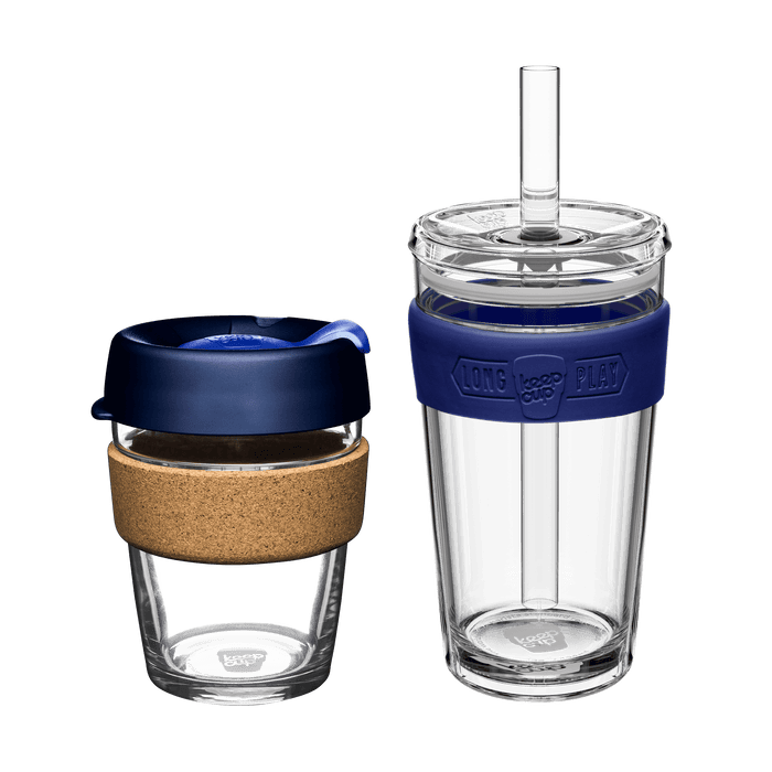 KeepCup Booked & Busy bundle in Ink colour featuring two reusable cups: a glass cup with cork band and navy blue lid on the left, and a clear double-walled LongPlay tumbler with navy silicone band and straw on the right, shown against a white background.
