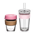Two KeepCup reusable cups in the Booked & Busy Pashmak Pink colourway displayed side by side on a white background: a glass coffee cup with cork band and pink plastic lid, and a taller clear tumbler with pink silicone band, clear lid and plastic straw.