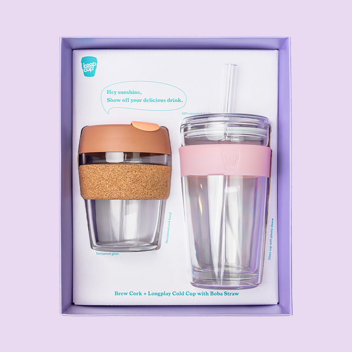 KeepCup Booked & Busy gift set featuring a Brew Cork cup with tempered glass and recovered cork band alongside a Longplay Cold Cup with pink plastic sleeve and boba straw, displayed in a lavender gift box.