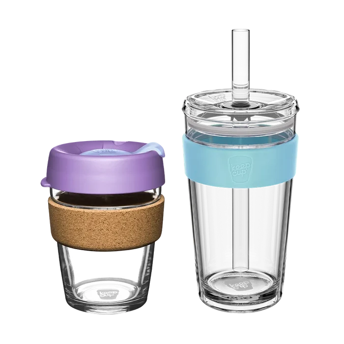 KeepCup Booked & Busy bundle featuring two reusable cups: a smaller glass Brew cup with cork band and lavender lid alongside a taller clear Longplay tumbler with light blue silicone band and straw, both displayed against a white background.