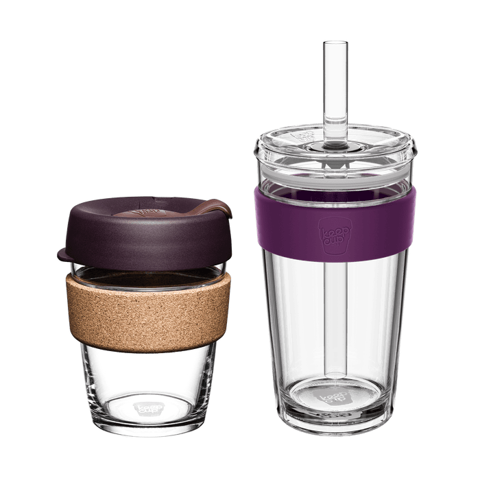 KeepCup Booked & Busy Alder set featuring two reusable cups: a smaller glass KeepCup with cork band and dark plum lid, alongside a larger clear double-walled tumbler with purple silicone band, clear lid and straw, shown on a white background.