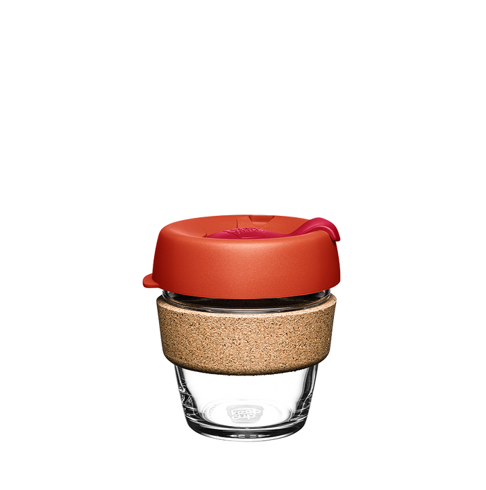 KeepCup Brew Cork XS 6oz in Daybreak colour, featuring a clear glass cup with natural cork band and warm orange-red lid with sipper closure, shown against a plain white background.