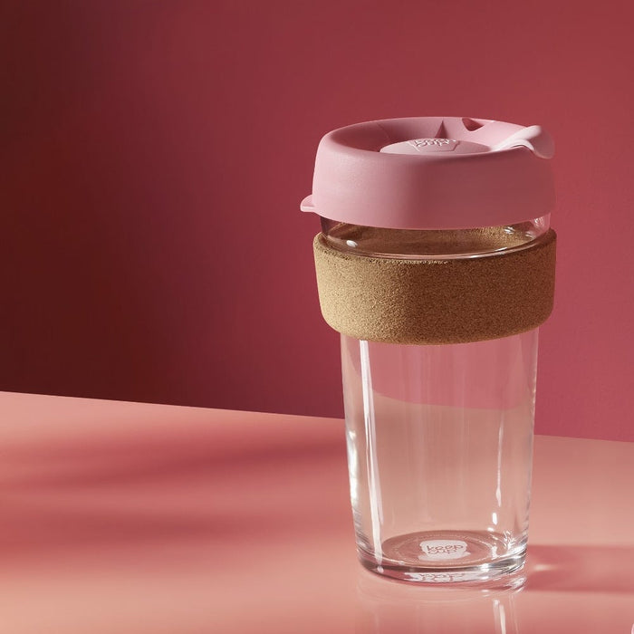 KeepCup Brew Cork L 16oz in Saskatoon, featuring a clear tempered glass cup with natural cork band and dusty pink lid, photographed on a pink surface against a deep rose background.