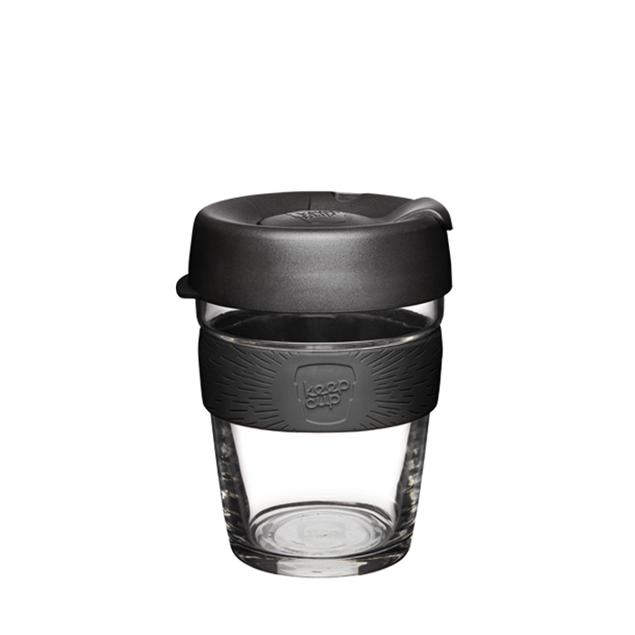 KeepCup Brew M 12oz in Black, featuring a clear tempered glass cup with a charcoal grey silicone band embossed with the KeepCup logo and a matching black plastic lid, shown against a white background.
