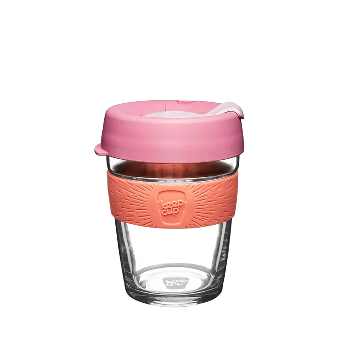 KeepCup Brew M 12oz in Tangerine, featuring a clear glass cup with a coral-coloured silicone band and dusty pink lid, shown against a white background.