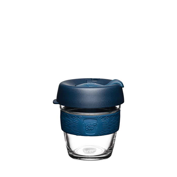 KeepCup Brew XS 6oz in Spruce, featuring a clear glass cup with a deep blue silicone band and matching navy lid with sipper opening, shown against a plain white background.