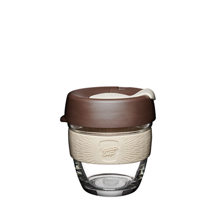 KeepCup Brew S 8oz in Roast colour, featuring a clear tempered glass cup with a cream-coloured silicone band embossed with the KeepCup logo and a brown plastic lid with sipper opening, photographed against a plain white background.