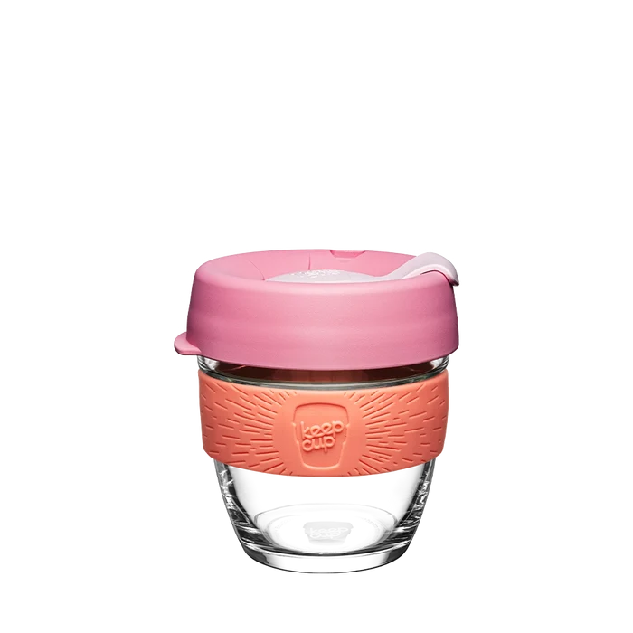 KeepCup Brew S 8oz in Tangerine, featuring a clear tempered glass cup with a coral silicone band and dusty pink lid with sipper, shown against a white background.