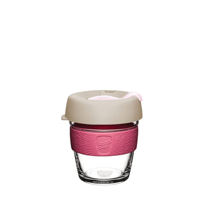 KeepCup Brew XS 6oz in Primrose, featuring a clear tempered glass cup with a dusty pink silicone band and beige lid with light pink plug, shown against a white background.