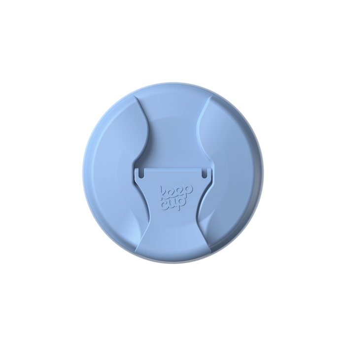 Top-down view of the Commuter Flip Lid in Orchid, showing the circular light blue lid with its distinctive flip-open drinking spout in the closed position, featuring the embossed KeepCup logo in the centre.