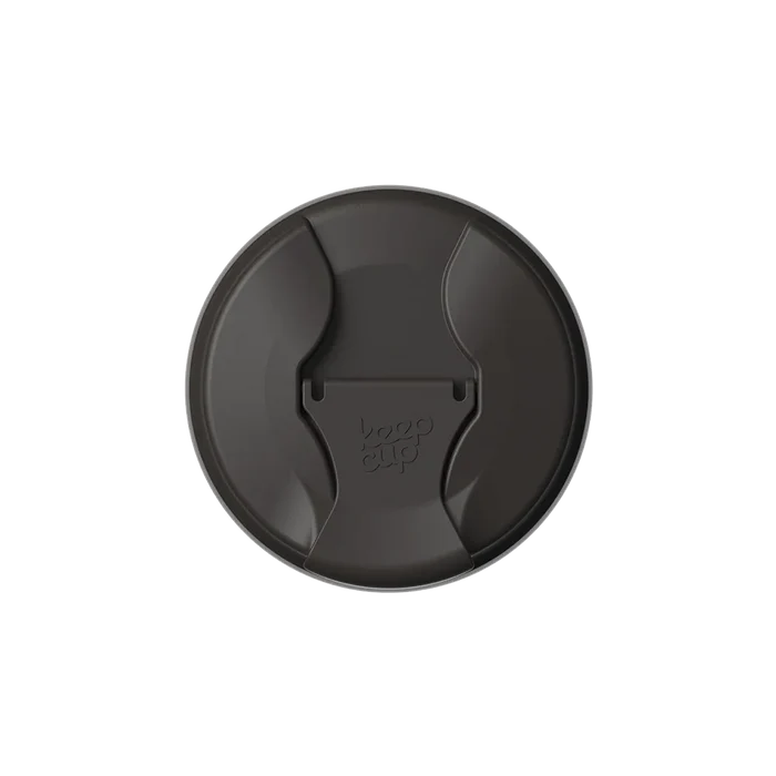 Top-down view of the KeepCup Commuter Flip Lid in Black, showing the circular lid with its distinctive curved sipper opening and flip closure featuring the embossed KeepCup logo.