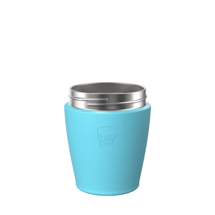 KeepCup Helix Stainless Steel Base in Cloud, a light blue silicone-wrapped stainless steel reusable cup shown from a front angle without its lid, displaying the embossed KeepCup logo on the exterior.