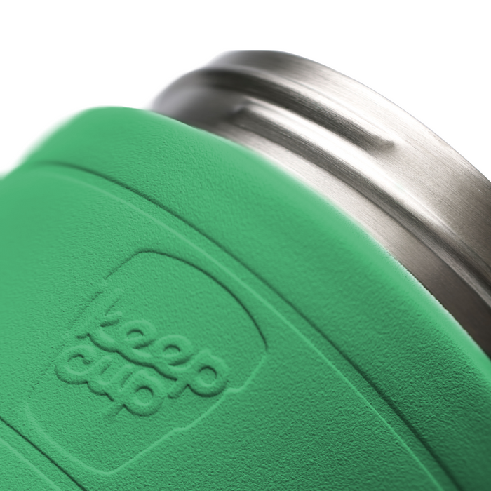 Close-up of a green KeepCup stainless steel base with the embossed 'keep cup' logo, showing a stainless steel rim on a white background.