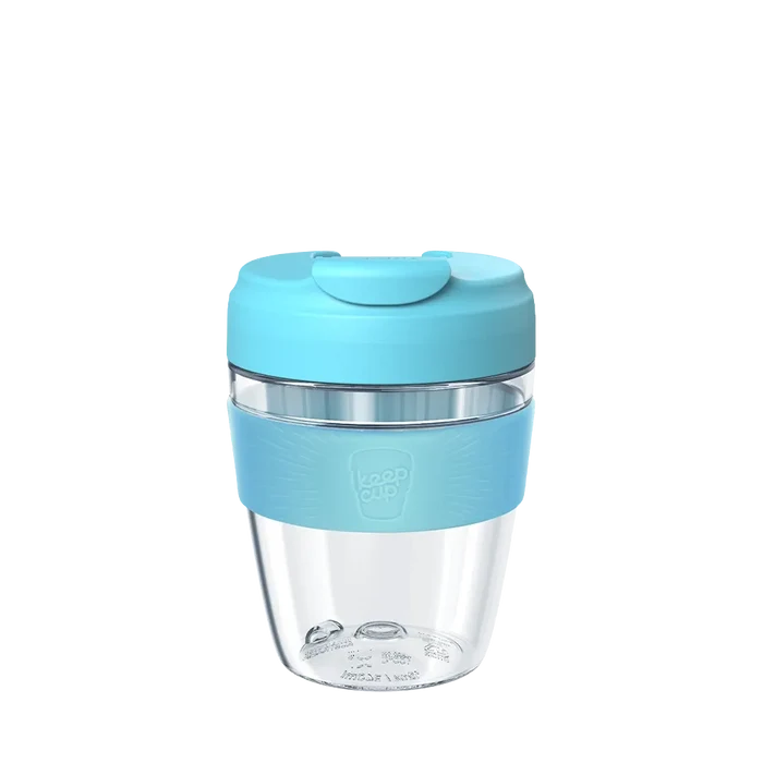 KeepCup Commuter Light M 12oz in Cloud colour, featuring a clear lightweight plastic cup with light blue silicone band and matching lid with sipper closure, shown against a white background.