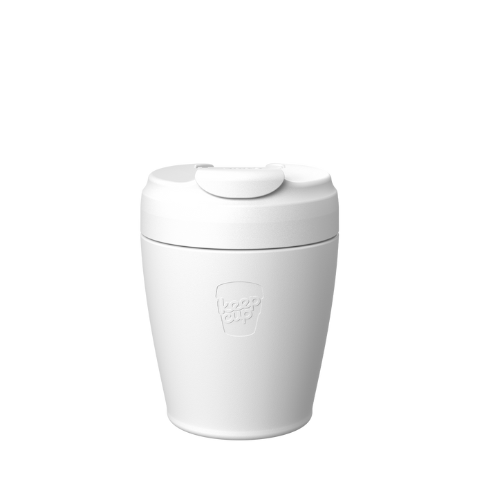 A white Design Your Own Commuter reusable coffee cup shown from a front angle against a plain white background, featuring the embossed KeepCup logo on the cup body and a flip-top lid with sipper closure.