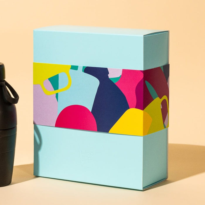 KeepCup Deskside Warrior Pashmak gift set featuring a matte black reusable bottle alongside a light blue gift box with colourful abstract illustrations of cups and vessels.