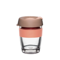 KeepCup Brew Longplay in Canna, medium 12oz size, shown against a white background. The reusable coffee cup features a clear double-walled glass body, peach-coloured silicone band with embossed KeepCup logo, and a taupe-toned lid with sipper opening.