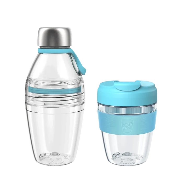 KeepCup Glow Getter set in Cloud colourway featuring a clear reusable water bottle with stainless steel cap and light blue silicone carry loop alongside a matching clear reusable coffee cup with light blue lid and grip band, shown against a white background.