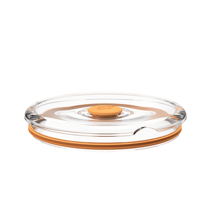 Go Bowl Flat Lid in Peach, shown from a low side angle against a white background, featuring a clear plastic lid with an orange silicone rim and central press-button seal.