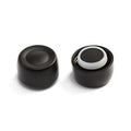 KeepCup Helix Bottle Cap in Black shown from two angles: the exterior view displaying the smooth matte black finish with concave top, and the interior view revealing the white silicone seal and ventilation slits.