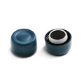 KeepCup Helix Bottle Cap in Storm colour shown from two angles: the cap base with its concave underside on the left, and an exploded view on the right displaying the internal components including the white silicone seal and black lid nested inside the dark teal outer shell.