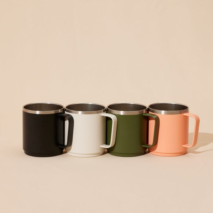 Four KeepCup Camp Mugs in a row showing the colour range, including the M 12oz Black alongside cream, olive green and peach variants, each featuring a stainless steel interior and matching handle.