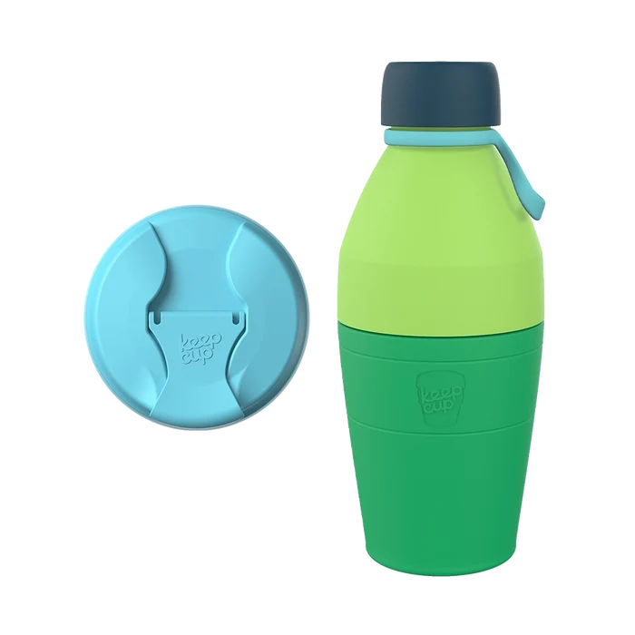 KeepCup Just Essentials in Emerald reusable bottle featuring a two-tone green body with dark navy cap and light blue carry loop, shown alongside a matching light blue sipper lid displaying the KeepCup logo.