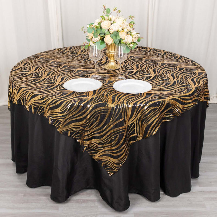 Elegant black and gold wave patterned tablecloth on round table with decorative flowers.