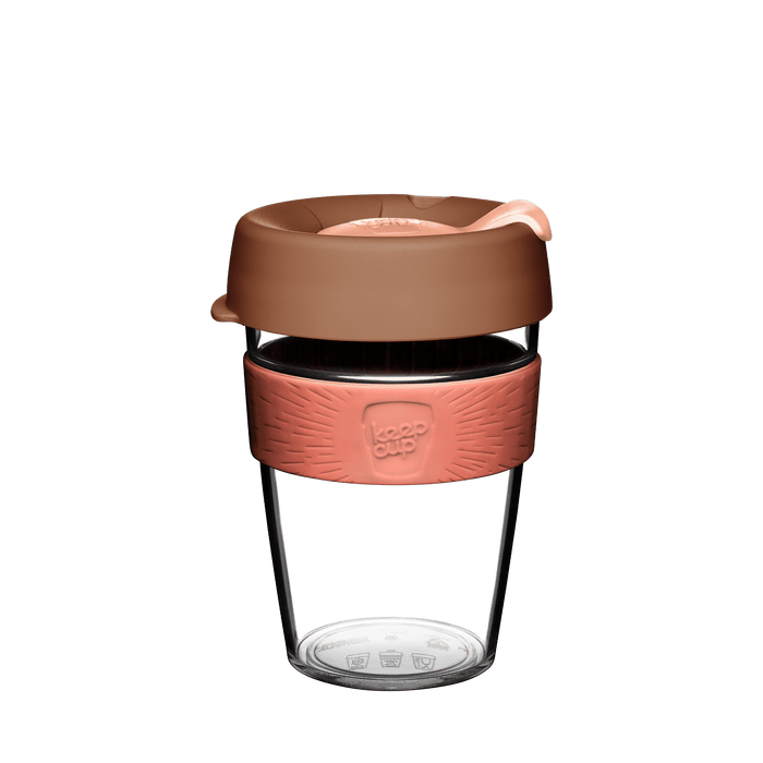 KeepCup Original Clear M 12oz in Frappe, featuring a clear reusable plastic cup with a coral-coloured silicone band embossed with the KeepCup logo, and a matte brown lid with peach-toned sipper, shown against a white background.