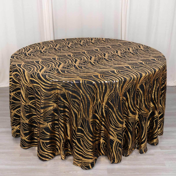 Round black and gold swirl tablecloth on a wooden surface.