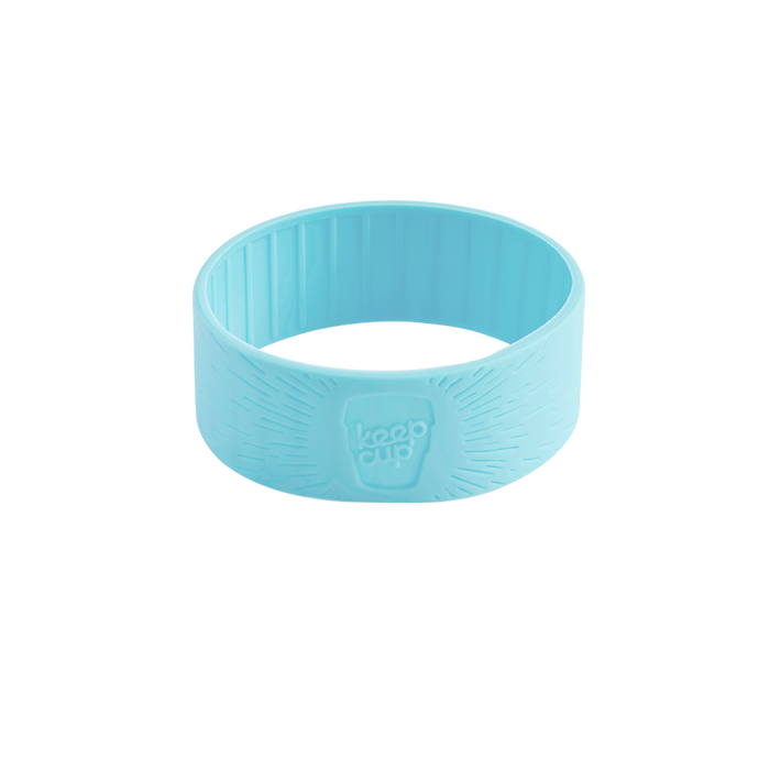 Light blue KeepCup Silicone Band in Cloud colour, shown at a three-quarter angle against a white background, featuring the embossed KeepCup logo and textured grip pattern on the exterior.
