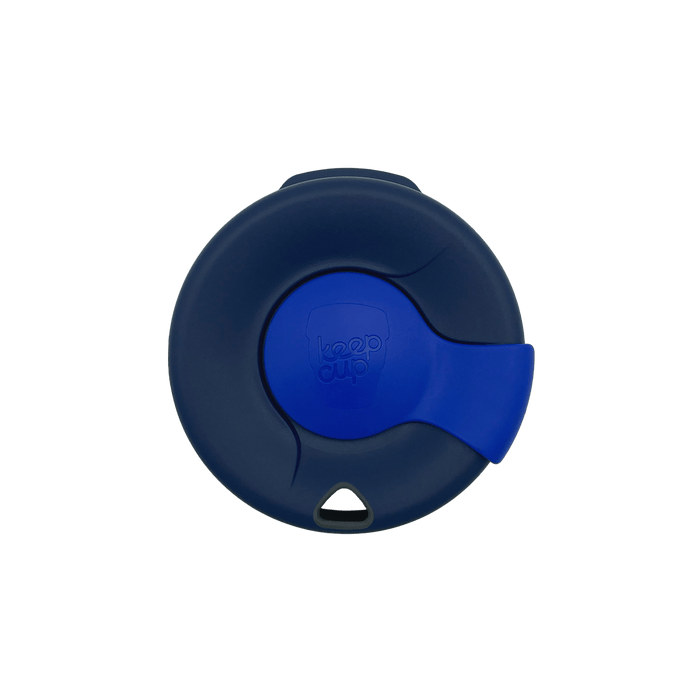 Top-down view of a KeepCup Splashproof Lid in dark navy with a bright blue sliding closure and embossed KeepCup logo in the centre.