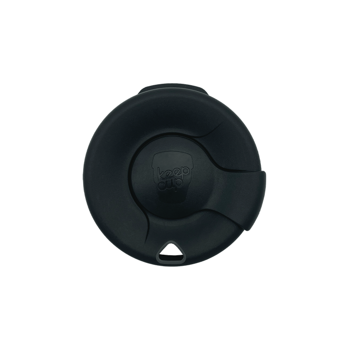 Top-down view of a black KeepCup Splashproof Lid, showing the circular design with embossed KeepCup logo in the centre, rotating closure mechanism, and small triangular vent hole.